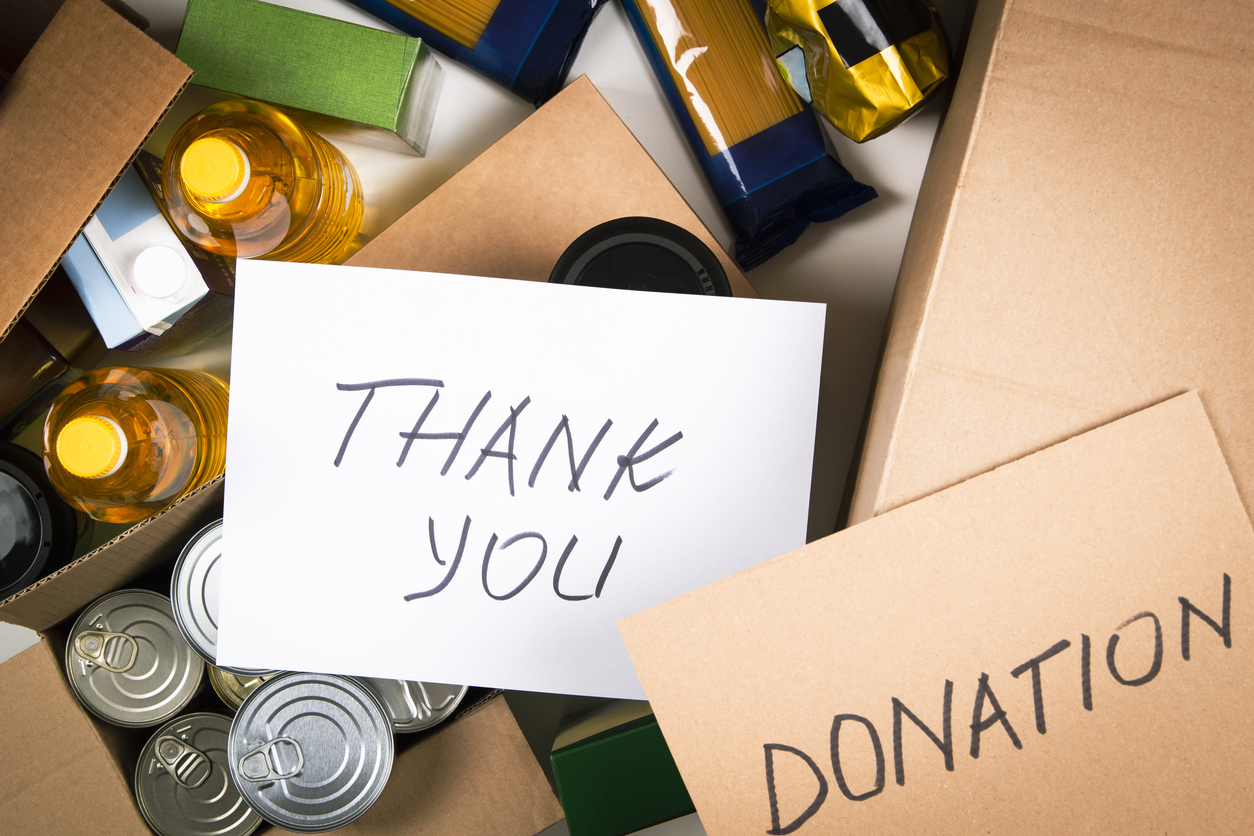 Food donations boxes with grocery products and cards with inscription Donation and Thank you. Cardboard boxes with oil, canned food, cereals, pasta, water. Top view